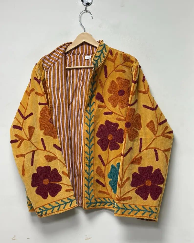 A ochre Suzani jacket with deep maroon flowers and a striped lining, shown open on a hanger