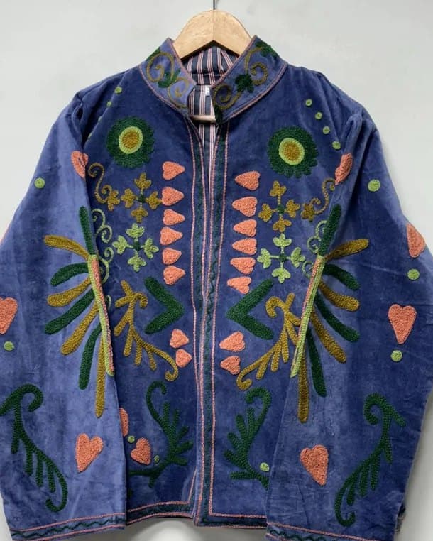 Close view of coral and green hand embroidery on periwinkle velvet