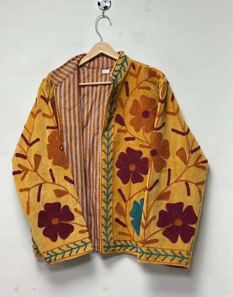An ochre Suzani jacket with deep maroon flowers, shown open on a hanger